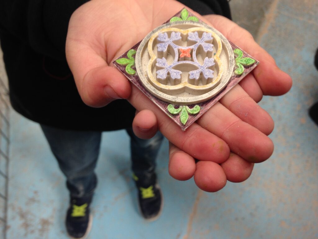Child holding a 3D printed and painted Minton tile